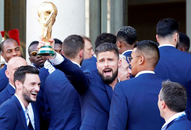 France player Olivier Giroud holds the trophy with teammates at the Elysee Palace