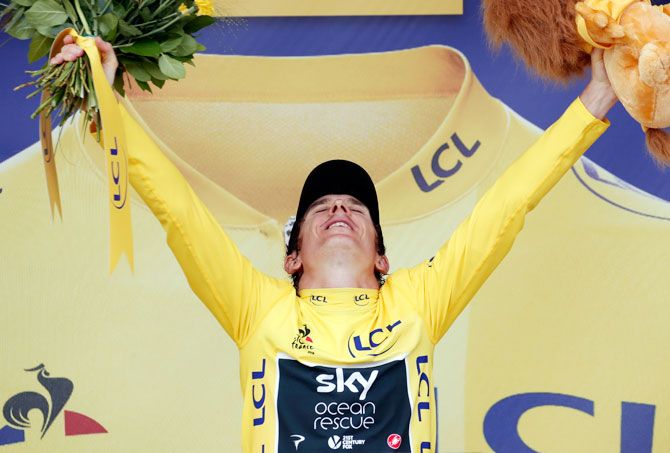 Team Sky rider Geraint Thomas of Britain celebrates on the podium, wearing the overall leader's yellow jersey on Saturday