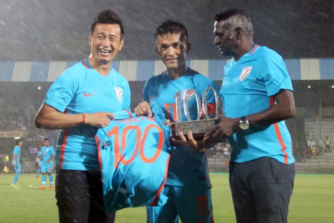 Indian football legends Bhaichung Bhutia, left, and I M Vijayan, right, present Sunil Chhetri with a trophy and a jersey to celebrate his 100th game for India. Photograph: AIFF Media