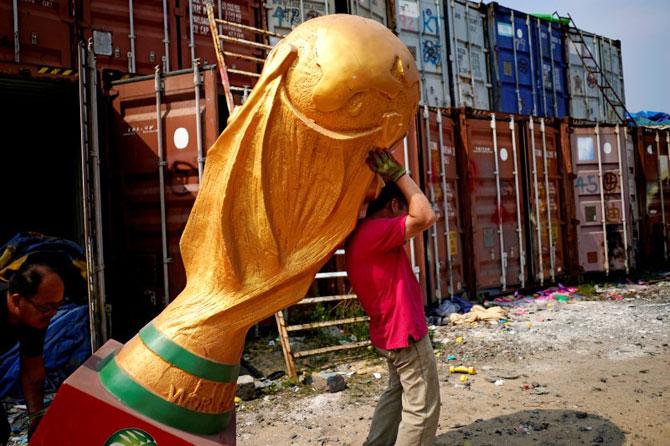 Workers work on a FIFA World Cup trophy replica at a small factory in the outskirts of Shanghai, China