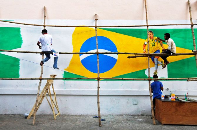 A painter applies finishing touches to an image of Brazil's Neymar, on a large Brazilian flag on a road side wall in Kolkata on June 9