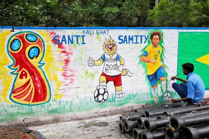 A painter applies finishing touches to an image of Brazil's Marcelo on a wall in Kolkata on June 4