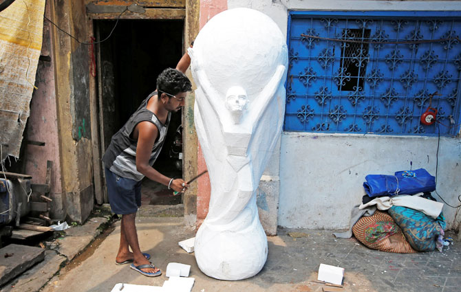 A man makes a replica of FIFA World Cup Trophy at a workshop in Kolkata on June 11