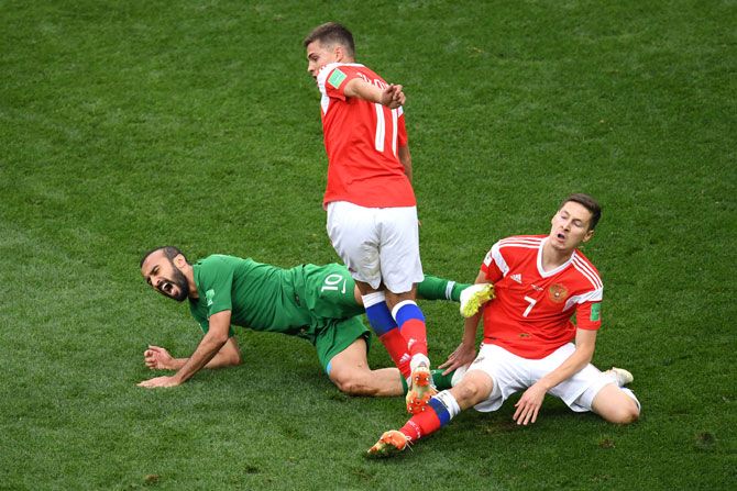Saudi's Mohammed Alsahlawi is tackled by Russia's Roman Zobnin and Daler Kuziaev