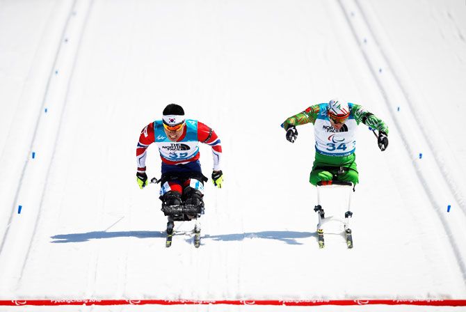 South Korea's Sin Eui-hyun (left) and Belarus' Dzmitry Loban race to cross the finish line during the men's 12.5km sitting biathlon