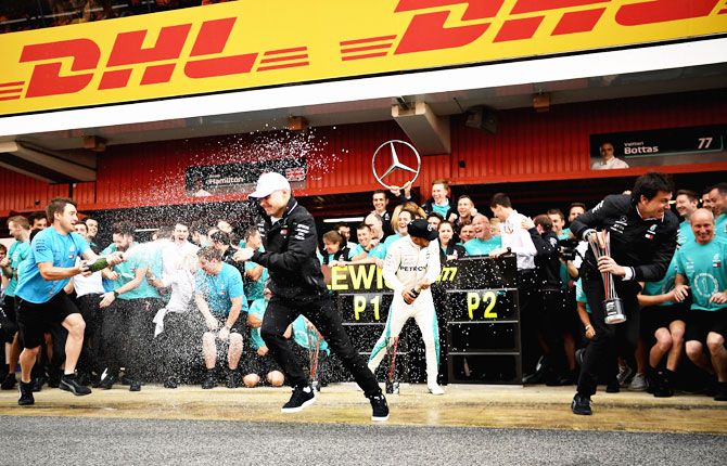Mercedes GP drivers Lewis Hamilton and second place finisher Valtteri Bottas are drenched in champagne by their team members after the Spanish Formula One Grand Prix