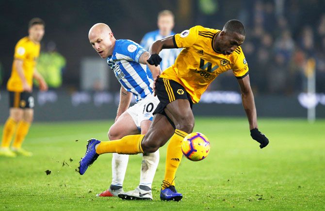 Wolverhampton Wanderers' Willy Boly and Huddersfield Town's Aaron Mooy vie for possession during their EPL match at Molineux Stadium on Wolverhampton on Sunday 