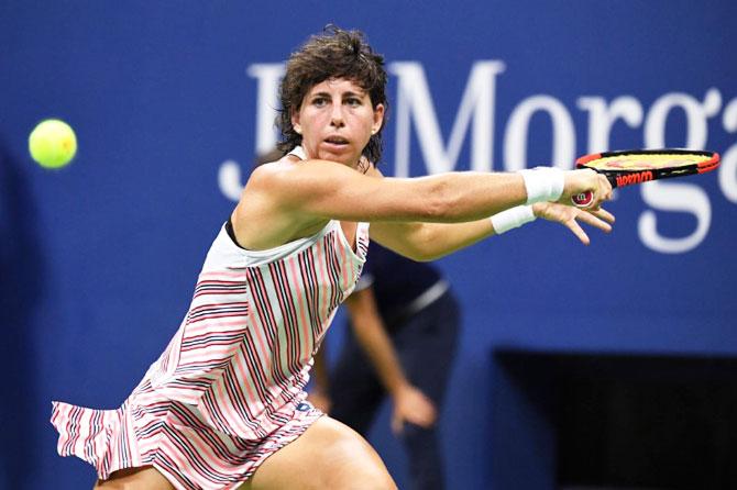 Spain's Carla Suarez Navarro returns a shot against Russia's Maria Sharapova