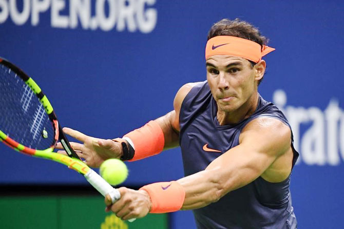 Rafael Nadal rushes to make a backhand return to Dominic Thiem