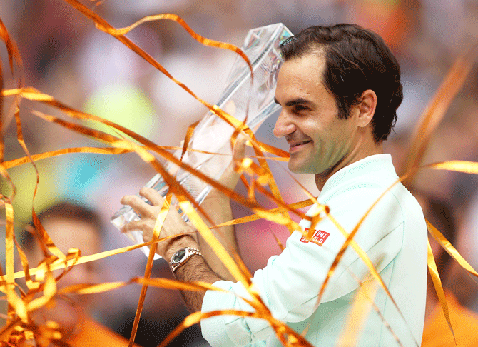 Switzerland's Roger Federer celebrates with the trophy after defeating John Isner to win the Miami Open final in Miami Gardens, Florida, on Sunday