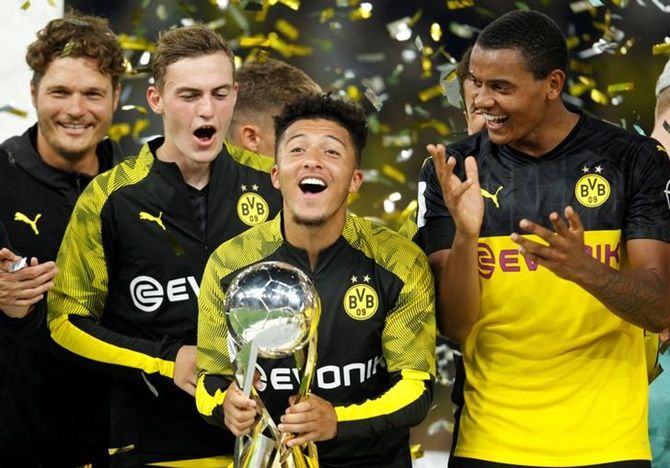 Jadon Sancho celebrates with the trophy after Borussia Dortmund beat Bayern Munich to win the German Super Cup.