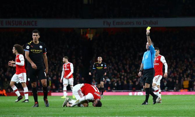 Manchester City's Rodri is shown a yellow card by referee Paul Tierney