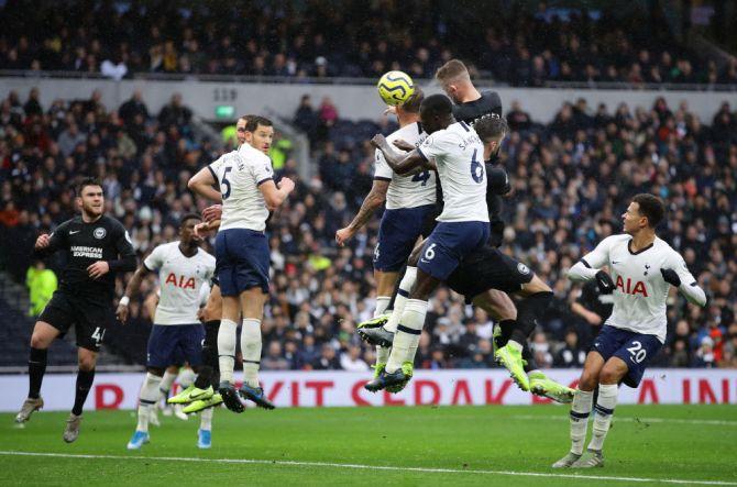 Brighton & Hove Albion's Adam Webster wins an aerial challenge against Tottenham's Davinson Sanchez to head in his team's first goal