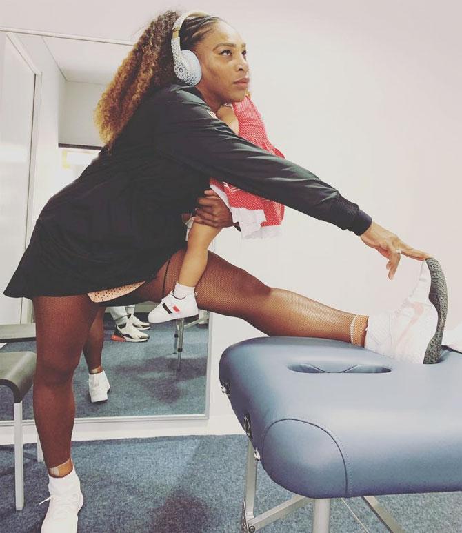 Serena Williams stretches while holding her baby Alexis Olympia before her Hopman Cup mixed match on Tuesday