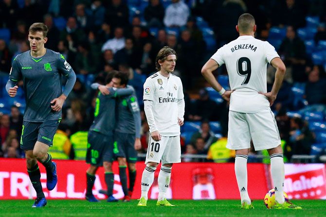 Real Madrid's Luka Modric (left) and his teammate Karim Benzema (right) reacts as Real Sociedad players celebrate their second goal during their La Liga match at Estadio Santiago Bernabeu in Madrid on Sunday