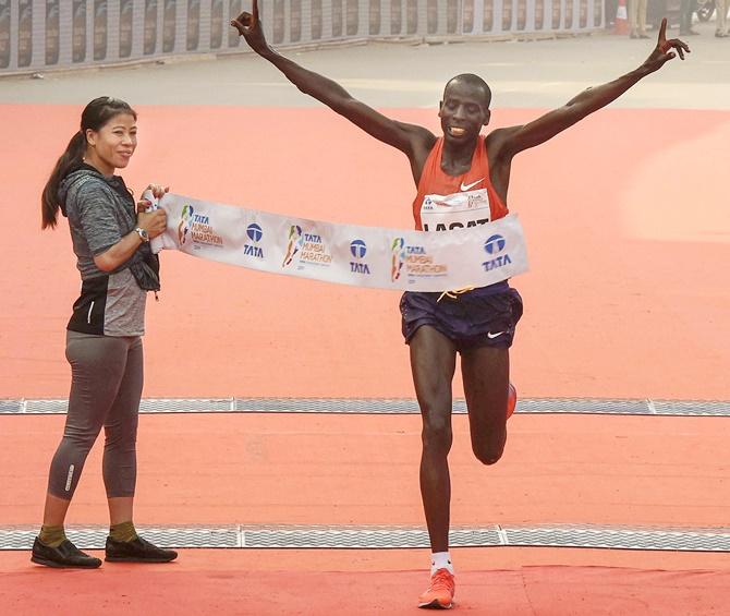 Kenya's Cosmas Lagat breasts the tape to win the Mumbai Marathon 2019 as champion boxer Mary Kom receives him at the finish line in Mumbai, January 20, 2019. Photograph: Shirish Shete/PTI