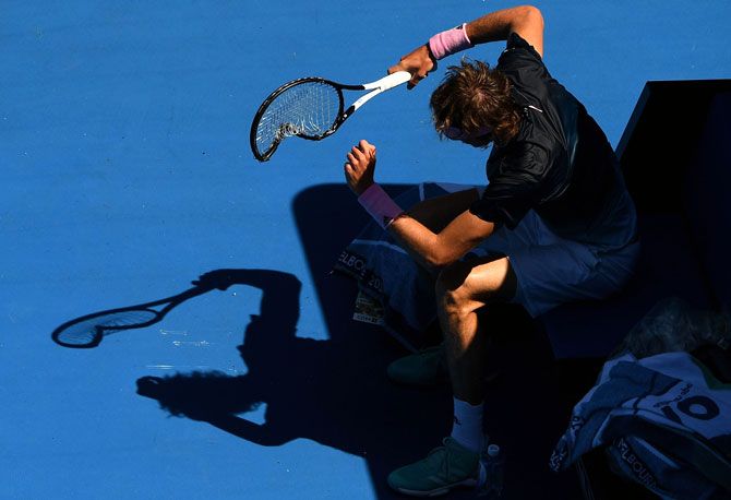 Alexander Zverev hammers his racket repeatedly into the ground to pick up a code violation warning from the umpire during his fourth round match against Canada's Milos Raonic on Monday, January 21