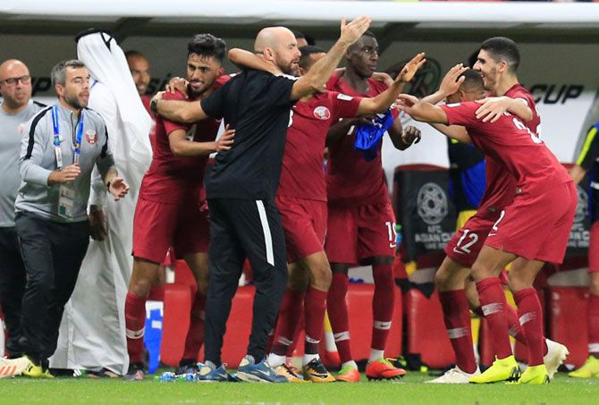 Qatar's Hamid Ismaeil celebrates with coach Felix Sanchez Bas and teammates after scoring their fourth goal against UAE on Tuesday