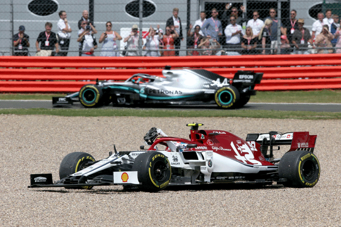 Alfa Romeo Racing's Italian driver Antonio Giovinazzi stops in the gravel trap as Mercedes' Lewis Hamilton makes his way into the pitlane during the Silverstone F1 Grand Prix