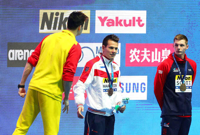 Gold medalist Sun Yang of China yells across at protesting Duncan Scott of Great Britain (right) as bronze medalists Martin Malyutin of Russia (centre) watches during the medal ceremony for the Men's 200m Freestyle Final at the 2019 FINA World Championships at Nambu International Aquatics Centre in Gwangju, South Korea, on Tuesday