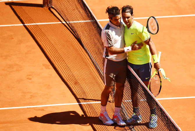 Rafael Nadal is congratulated by and Roger Federer at the net