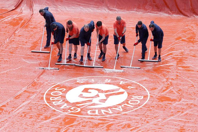 Grounds staff clean the court during the men's semi-final betweeen Serbia's Novak Djokovic and Austria's Dominic Thiem at Roland Garros in Paris on Saturday