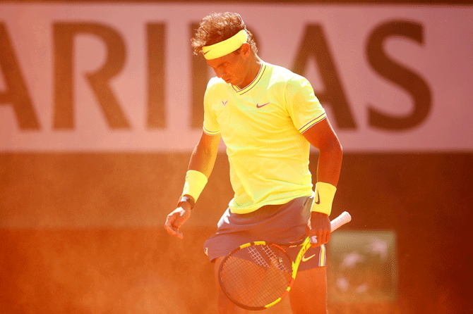 Spain's Rafael Nadal shields himself from the clay kicking up in the wind