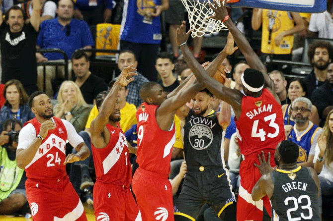 Golden State Warriors guard Stephen Curry (30) handles the ball while Toronto Raptors center Serge Ibaka (9) and forward Pascal Siakam (43) defend during the second half in game six of the 2019 NBA Finals at Oracle Arena