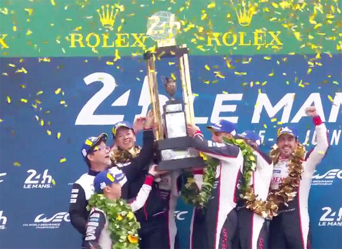 Fernando Alonso (extreme right) celebrates on the podium with his Toyota team mates Kazuki Nakajima and Switzerland's Sebastien Buemi after winning the Le Mans 24 Hours sportscar race on Sunday