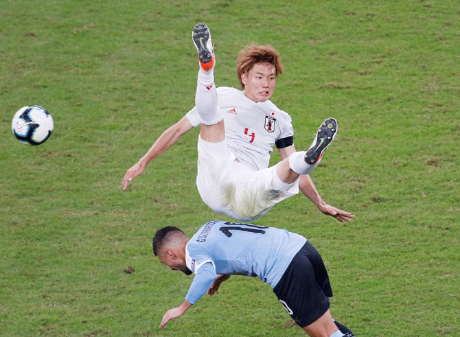 Japan's Ko Itakura falls over Uruguay's Giorgian de Arrascaeta as they vie for possession