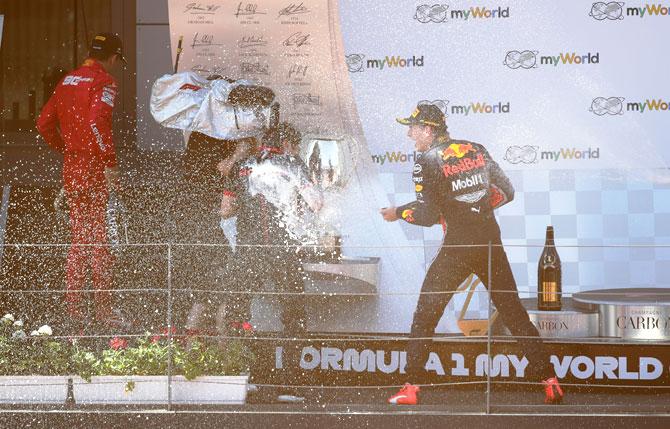 Red Bull's Max Verstappen celebrates on the podium after winning the race as second placed Ferrari's Charles Leclerc walks off