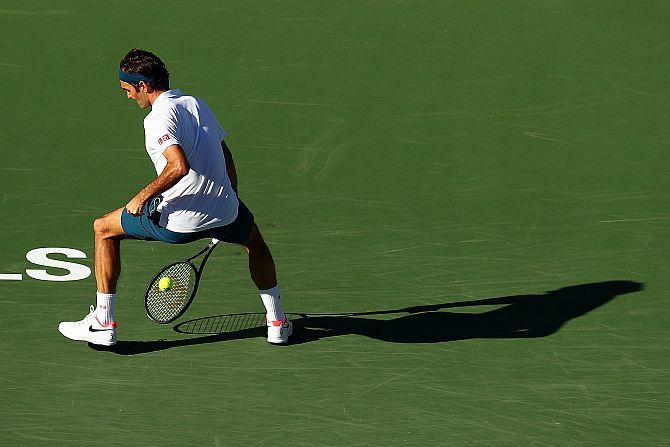 Switzerland's Roger Federer plays a 'tweener' as he returns against Austria's Dominic Thiem during the BNP Paribas Open men's singles final at the Indian Wells Tennis Garden in Indian Wells, California, on Sunday