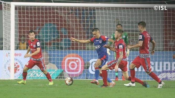 Bengaluru's Sunil Chhetri is challenged by a host of Jamshedpur defenders.