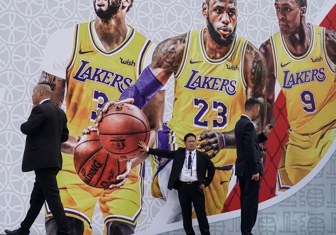 Security personnel stand in front of a billboard with an image of Los Angeles Lakers basketball players