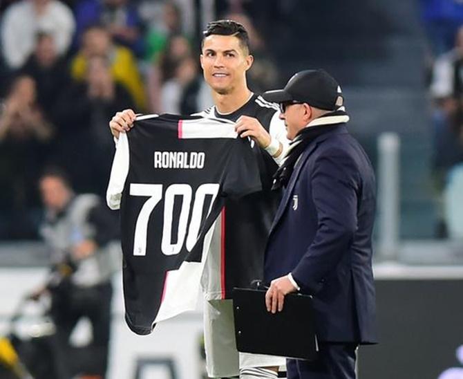 Juventus's Cristiano Ronaldo holds up a shirt to commemorate his 700 career goals before the match against Bologna.