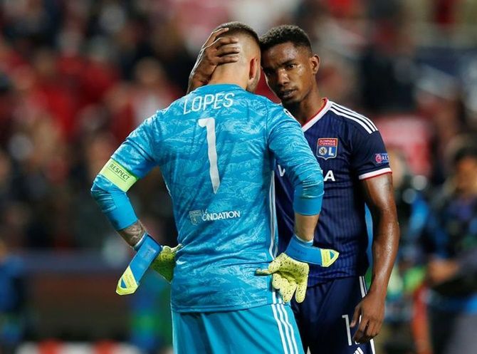 Olympique Lyonnais goalkeeper Anthony Lopes is consoled by teammate Thiago Mendes after the Group G match against Benfica
