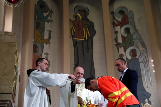 A Franciscan priest baptizes triathlon champion Akos Vanek as a gesture to honor his voluntary service as a paramedic during Easter Saturday service amid the coronavirus disease (COVID-19) outbreak in Budapest, Hungary, on April 11
