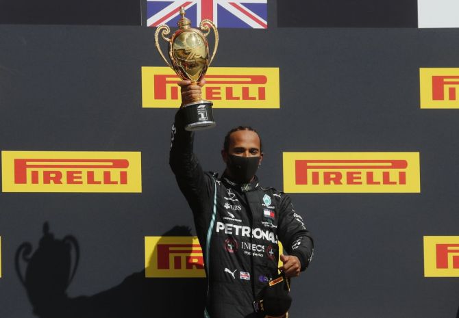 Mercedes' Lewis Hamilton celebrates on the podium with the trophy winning the race