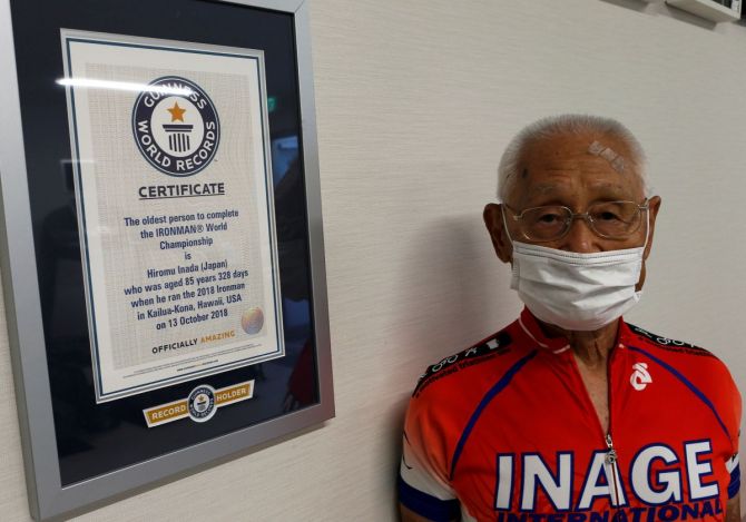Hiromu Inada (87), record holder of the oldest person to complete an Ironman World Championship, poses next to his certificate from Guinness World Record at his training facility in Chiba, near Tokyo, Japan