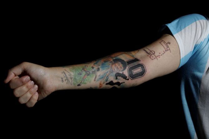 Maximiliano Fernando, a devoted Diego Maradona fan who has images of Maradona tattooed on his arm, poses for a photo at Leda Ink tattoo studio in Buenos Aires