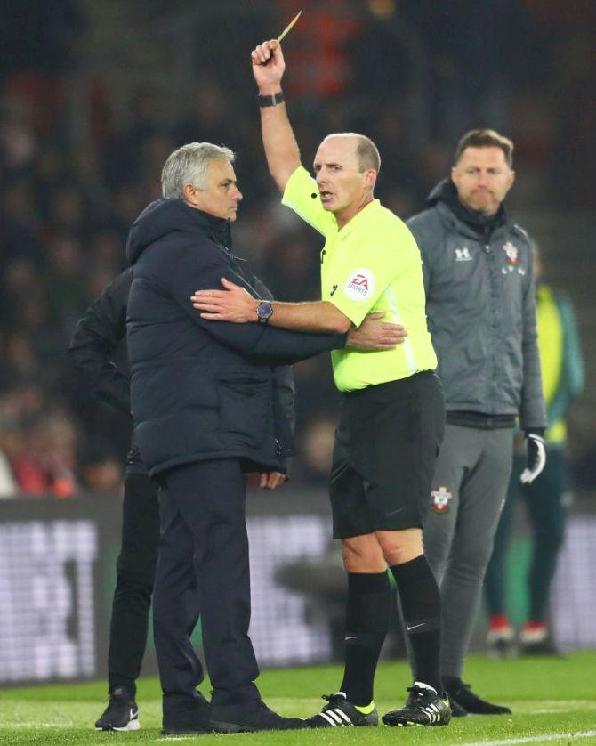 Match referee Mike Dean shows a yellow card to Tottenham Hotspur manager Jose Mourinho, during the Premier League match against Southampton FC at St Mary's Stadium in Southampton. Mourinho was booked for an altercation with the home coaching staff