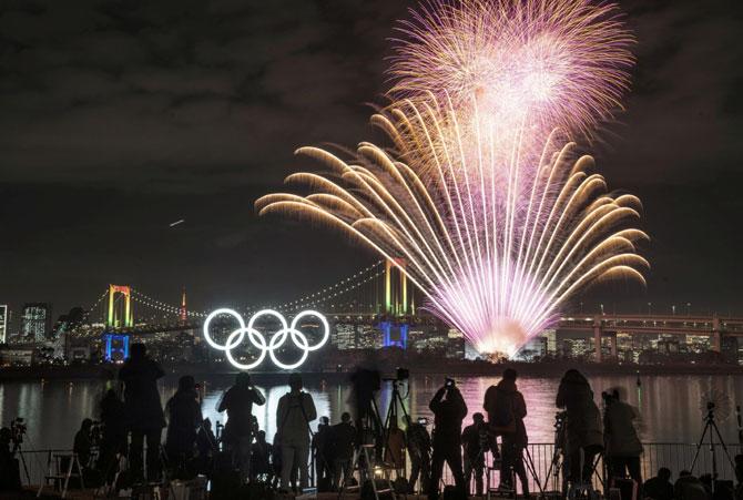 Fireworks light up the sky near the illuminated Olympic rings at a ceremony to mark six months before the start of the 2020 Olympic Games in Tokyo.