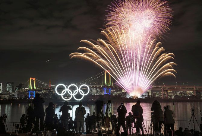Fireworks light up the sky near the illuminated Olympic rings at a ceremony to mark six months before the start of the 2020 Olympic Games in Tokyo.