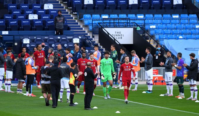 The Manchester City team create a guard of honor for the Liverpool FC team as Liverpool's Jordan Henderson leads his team out prior to their Premier League match