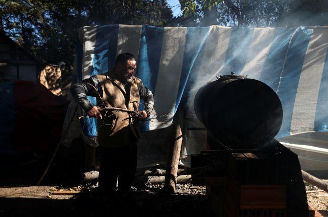 Edmundo Hernandez, father of Sebastian Galleguillo, adds wood to a fire to heat the water of the swimming pool the family built for Sebastian