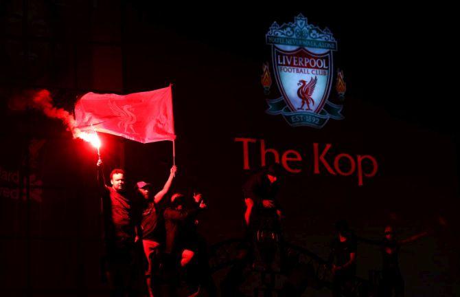 Liverpool fans celebrate outside Anfield Stadium after their team won the Premier League title following Chelsea's win over Manchester City on Thursday