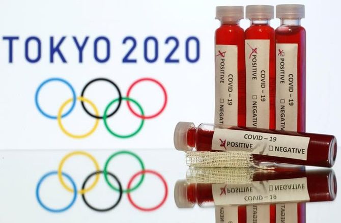 Fake blood in seen in test tubes labelled with coronavirus disease (COVID-19) in front of a displayed Tokyo 2020 Olympics logo in this illustration.