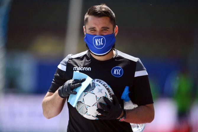 A ball boy disinfects a ball 