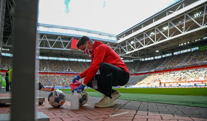 A staff member wipes down the footballs with a cloth so they are disinfected during the Bundesliga match between Fortuna Duesseldorf and SC Paderborn 07 at Merkur Spiel-Arena in Duesseldorf, Germany, on Saturday