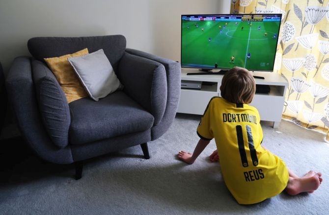 A young boy watches the Bundesliga match between Borussia Dortmund and FC Schalke 04 live on TV in Wallington, England on Saturday